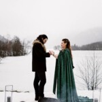 Couple de mariés main dans la main face au lac.