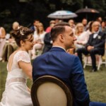 Le couple de mariés pris en photo de dos avec en fond les invités.