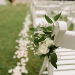 Roses blanches nouées sur les chaises de la cérémonie.