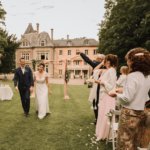 Couple de mariés remontant l'alllée sous les pétales de fleurs.