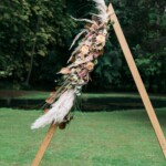 Arche en forme de triangle décorée avec de la pampa et des roses aux couleurs pastels.
